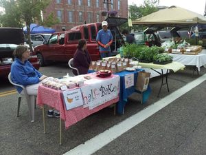 Two people sit behind a table selling baked goods at the farmer's market in Downtown Wooster. 