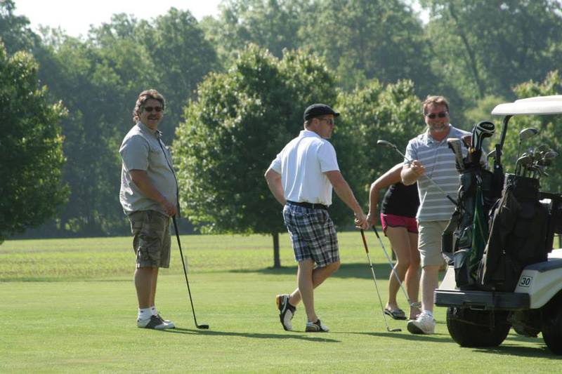 A group of men and women playing golf. 