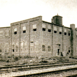 A view of a factory building from its railroad tracks. 