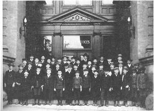 A group of about 45 boys posing on the stairs to a large building, circa 1902. 