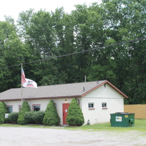 A front view of a small, white, one-story building with a flagpole out front which is the Moose Lodge. 