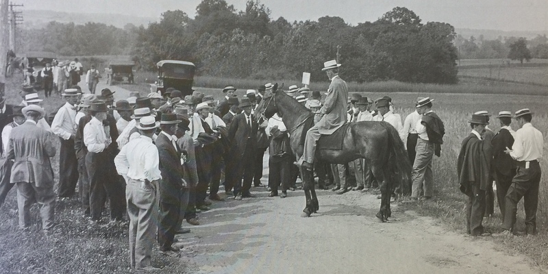 A crowd standing around Charles Thorne who is sitting on a horse, circa 1918. 