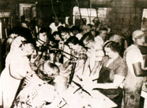 Women gathered around a large table cooking. 