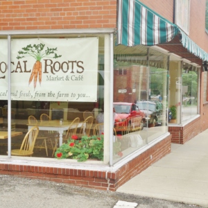 The front window of Local Roots Market and Cafe, with tables and chairs inside. 