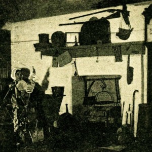 A fireplace from the pioneer era with a rifle hanging above it. 