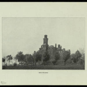 A photograph of old main circa 1884. Old main was a large brick building with a tower, surrounded by trees. 