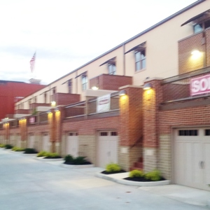 An apartment building with a garage on the bottom half and windows on the top half. 